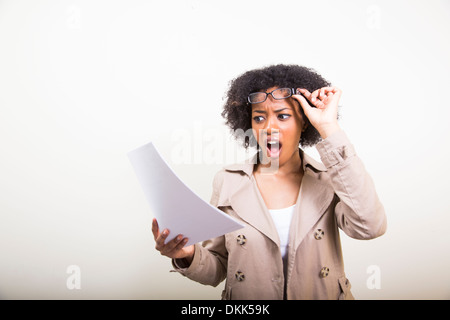 Young African American woman reading documents looking shocked Stock Photo