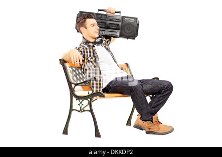 Guy holding a boombox on his shoulder and sitting on a wooden bench Stock Photo