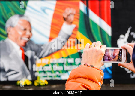 Belfast, Northern Ireland. 7th Dec 2013 - A woman takes a photograph of the Nelson Mandela Mural using an iPhone. Credit:  Stephen Barnes/Alamy Live News Stock Photo
