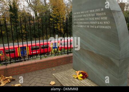 Clapham Junction, London, UK. 5th Dec, 2013.  Flowers laid at the Clapham Junction rail disaster memorial mark the 25th anniversary of the accident on December 13 as a train rushes by.  35 people were killed and  100 injured after 3 trains collided during the morning Credit:  On Sight Photographic/Alamy Live News Stock Photo