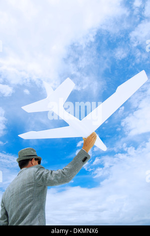 Entrepreneur businessman holds white model airplane flying in blue sky Stock Photo