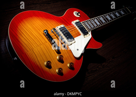 Cherry sunburst Les Paul guitar on dark brown wooden floor Stock Photo