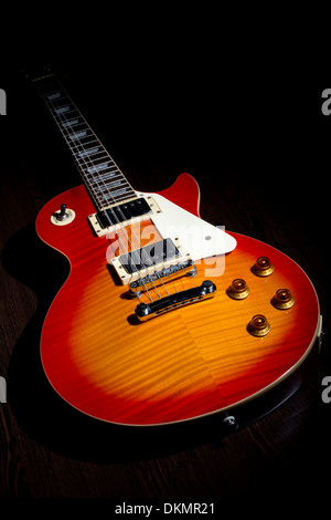 Cherry sunburst Les Paul guitar on dark brown wooden floor Stock Photo