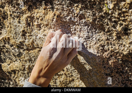 a woman climber hand grabbing a small rock hold with a crimp grip Stock Photo