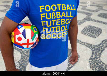 Brazilian soccer player wears international football shirt carrying a ball with World Cup team flags Stock Photo