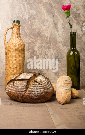 A loaf of fresh rye bread with a wine bottle and red carnation Stock Photo
