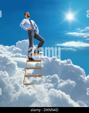 Laughing confident businessman standing at the top of ladder high in the sky Stock Photo