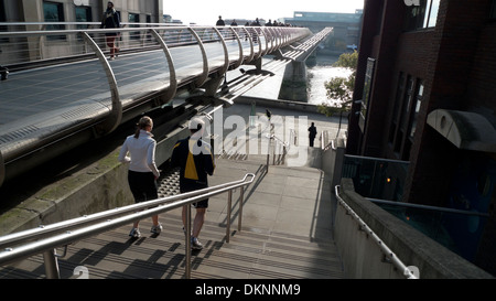 Rear back couple joggers runners people running down steps under Millennium Bridge winter River Thames view of London UK Great Britain KATHY DEWITT Stock Photo