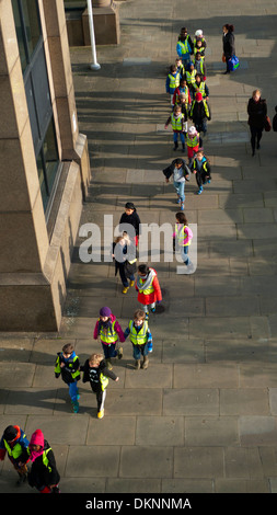 A group of young schoolchildren outdoors on a field trip viewed from above, walking along the bank of the Thames in London KATHY DEWITT Stock Photo