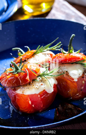 Oven roasted tomatoes stuffed with cheese in a blue pan Stock Photo