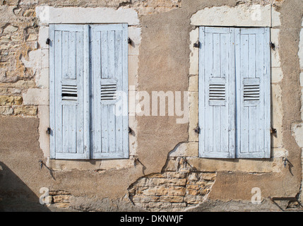 Closed faded blue shutters and crumbling plaster on a house in Santenay, Burgundy, France Stock Photo