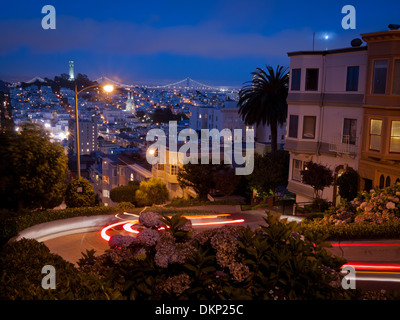 A night view looking down Lombard Street in San Francisco.  Coit Tower and the Bay Bridge are in the distance. Stock Photo