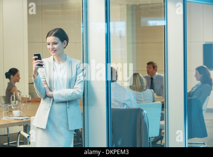 Businesswoman using cell phone in meeting Stock Photo