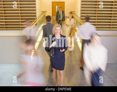 Businesswoman walking in busy office corridor Stock Photo