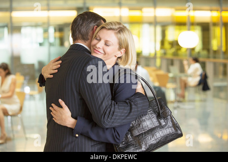 Business people hugging in office Stock Photo