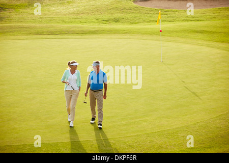 Senior couple walking on golf course Stock Photo