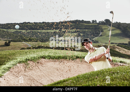 Man swinging from sand trap on golf course Stock Photo