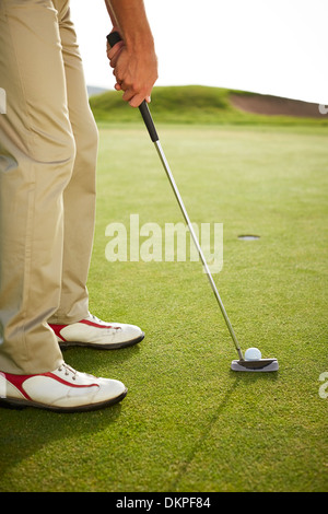 Man preparing to putt on golf course Stock Photo