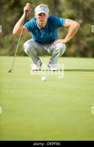 Man preparing to putt on golf course Stock Photo