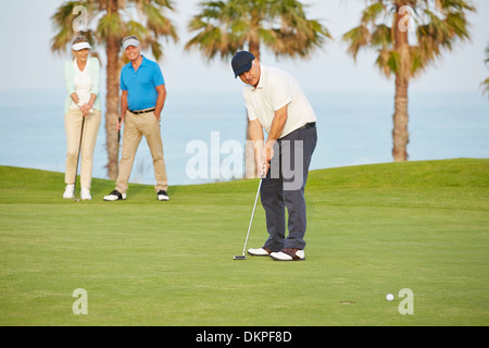 Senior friends playing golf on course Stock Photo