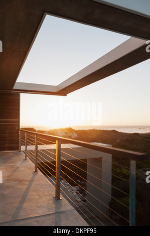 Balcony of modern house overlooking ocean at sunset Stock Photo