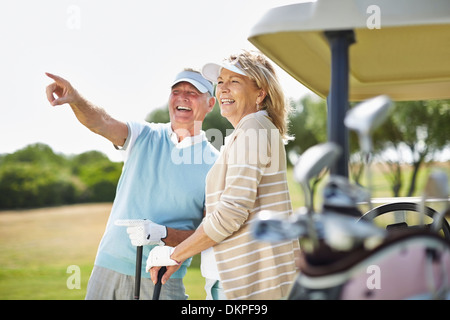 Senior couple standing next to golf cart Stock Photo