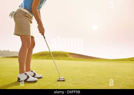 Woman putting on golf course Stock Photo