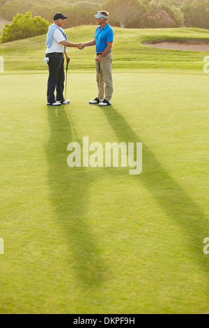 Senior men shaking hands on golf course Stock Photo