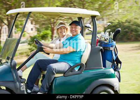 Senior couple driving golf cart on course Stock Photo
