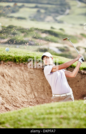 Woman swinging from sand trap on golf course Stock Photo