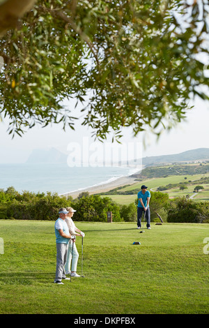 Older friends playing golf on course Stock Photo
