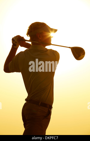 Silhouette of man swinging golf club Stock Photo