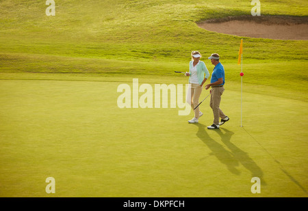 Senior couple walking on golf course Stock Photo