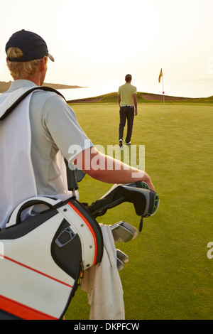 Golfer and caddy nearing golf flag Stock Photo