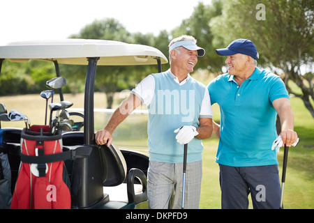 Senior men laughing next to golf cart Stock Photo