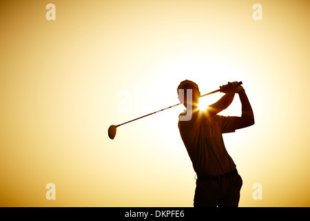 Silhouette of man swinging golf club Stock Photo