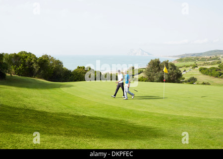 Men walking on golf course overlooking ocean Stock Photo