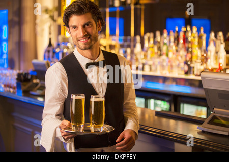 Portrait of well dressed bartender carrying beers on tray Stock Photo