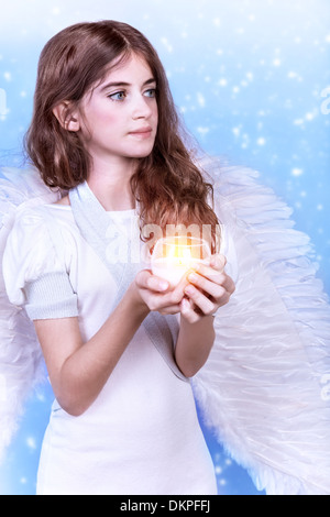 Holy angel, adorable girl with candle and wings on blue background, Christmastime holidays, dreaming and praying concept Stock Photo