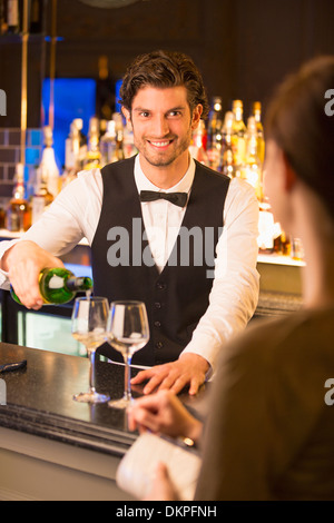 Well dressed bartender pouring wine for customer in luxury bar Stock Photo