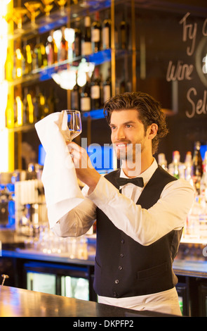 Well dressed bartender wiping wine glass in luxury bar Stock Photo