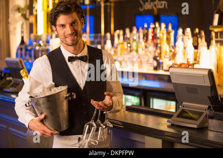 Portrait of well dressed bartender holding champagne bucket in luxury bar Stock Photo