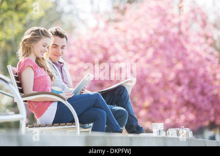 Couple relaxing together on park bench Stock Photo