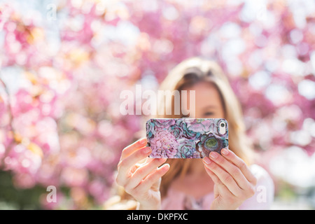 Woman taking self-portrait with cell phone outdoors