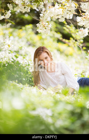 Woman relaxing in grass with book Stock Photo