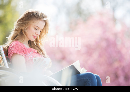 Woman reading book on park bench Stock Photo