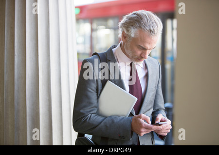 Businessman using cell phone on city street Stock Photo