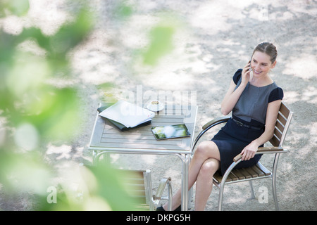 Businesswoman sitting at sidewalk cafe Stock Photo