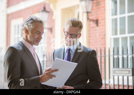 Businessmen looking at paperwork outdoors Stock Photo