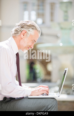 Businessman using laptop outdoors Stock Photo